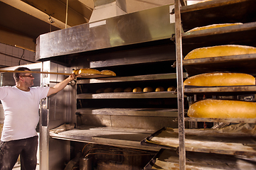 Image showing bakery worker taking out freshly baked breads