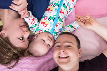 Image showing Top view of smiling young couple lying with their baby