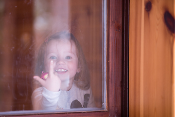 Image showing little cute girl playing near the window