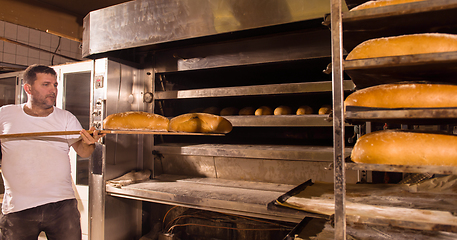 Image showing bakery worker taking out freshly baked breads