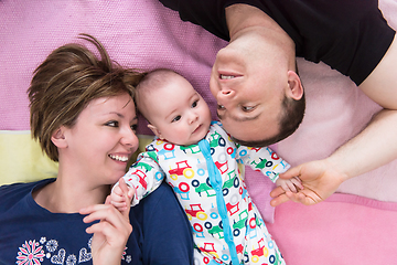 Image showing Top view of smiling young couple lying with their baby