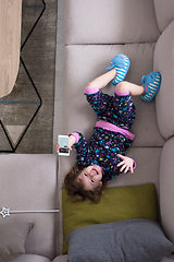 Image showing top view of little girl using a smartphone on the sofa