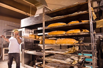 Image showing bakery worker taking out freshly baked breads