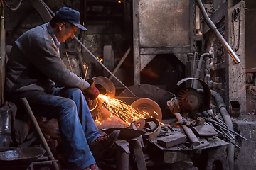 Image showing the blacksmith polishing metal products