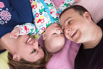 Image showing Top view of smiling young couple lying with their baby