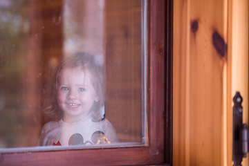 Image showing little cute girl playing near the window