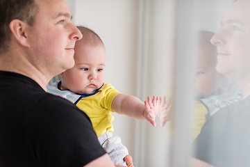 Image showing young father holding baby near the window at home