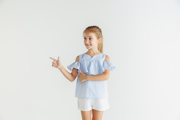 Image showing Little smiling girl posing in casual clothes on white studio background
