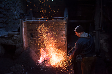 Image showing young traditional Blacksmith working with open fire