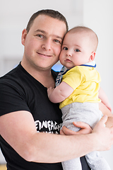 Image showing young father holding baby near the window at home