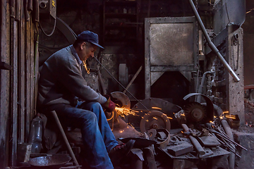 Image showing the blacksmith polishing metal products