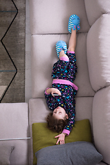 Image showing top view of little girl using a smartphone on the sofa