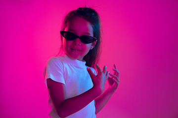 Image showing Portrait of little girl in headphones on purple gradient background in neon light