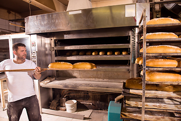 Image showing bakery worker taking out freshly baked breads