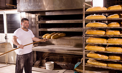 Image showing bakery worker taking out freshly baked breads