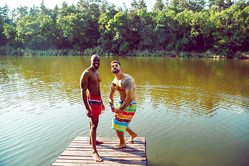 Image showing Happy friends having fun, ready to jump and swim in river