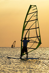 Image showing Silhouettes of a windsurfers on waves of a bay