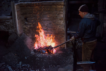 Image showing young traditional Blacksmith working with open fire