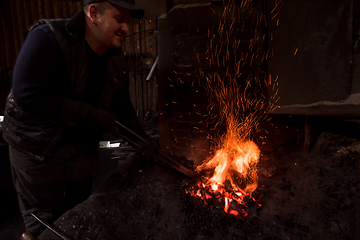 Image showing young traditional Blacksmith working with open fire