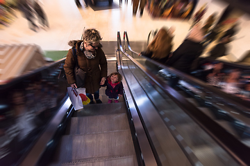 Image showing young mother and her little daughter on escalator in shopping ma