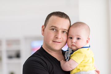 Image showing young father holding baby near the window at home