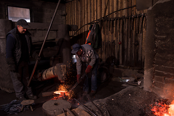 Image showing blacksmith workers using mechanical hammer at workshop