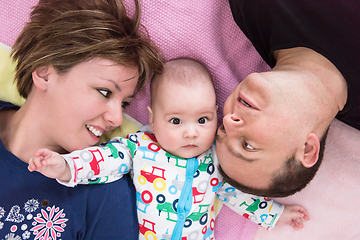 Image showing Top view of smiling young couple lying with their baby