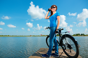 Image showing Young woman is standing in front of her bicycle