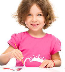 Image showing Little girl is painting with gouache