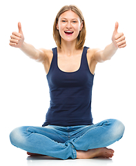 Image showing Young happy woman is showing thumb up sign