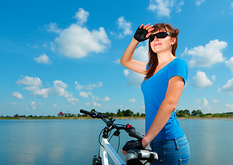 Image showing Young woman is standing behind of her bicycle