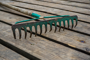 Image showing Old rake on the wooden planks. 