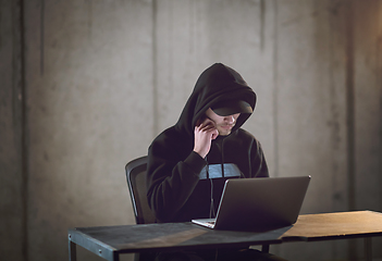 Image showing talented hacker using laptop computer while working in dark offi