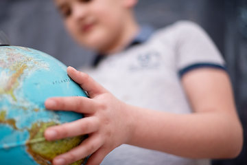 Image showing boy using globe of earth in front of chalkboard