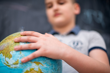 Image showing boy using globe of earth in front of chalkboard