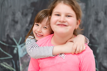 Image showing little girls hugging in front of chalkboard