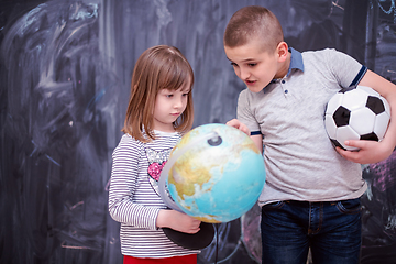 Image showing boy and little girl using globe of earth in front of chalkboard