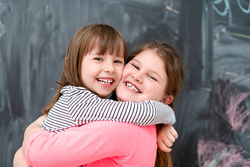 Image showing little girls hugging in front of chalkboard