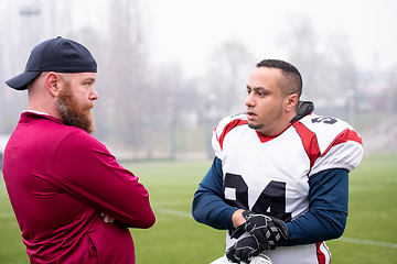 Image showing american football player discussing strategy with coach