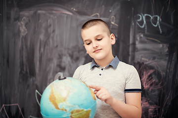 Image showing boy using globe of earth in front of chalkboard