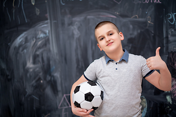 Image showing happy boy holding a soccer ball in front of chalkboard