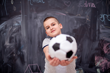 Image showing happy boy holding a soccer ball in front of chalkboard