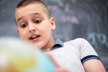 Image showing boy using globe of earth in front of chalkboard