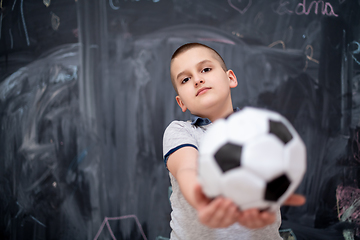 Image showing happy boy holding a soccer ball in front of chalkboard