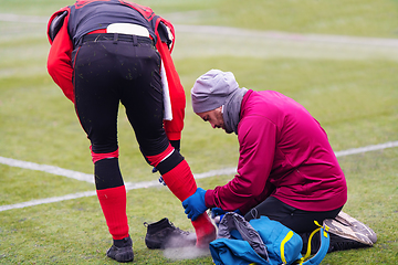 Image showing Sports doctor using freezing spray while treating injured sportm