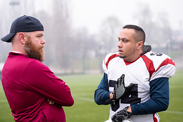 Image showing american football player discussing strategy with coach