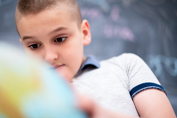 Image showing boy using globe of earth in front of chalkboard