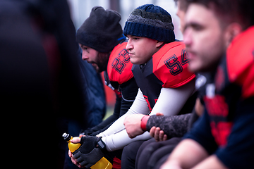 Image showing american football player resting with teammates