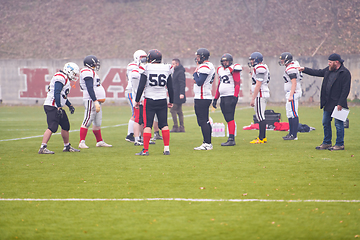 Image showing american football players discussing strategy with coach