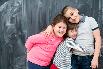 Image showing group of kids hugging in front of chalkboard